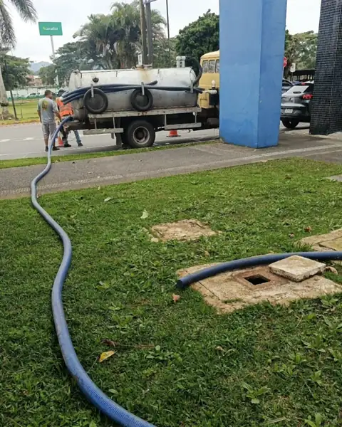 Caminhão da Meira atendendo área comercial em Joinville, com mangueira até a caixa de esgoto