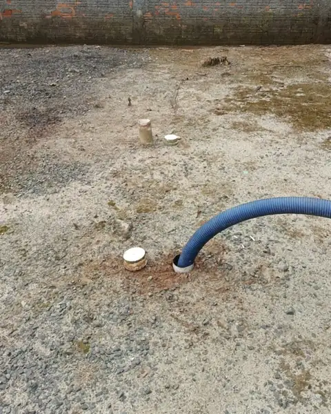 Mangueira do caminhão conectada à fossa em um terreno durante a limpeza
